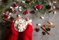 Hot chocolate cup and marshmallows in female hand wearing red sweater, against grey background & Christmas theme Royalty Free Stock Photo