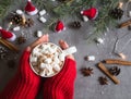 Hot chocolate cup and marshmallows in female hand wearing red sweater, against grey background & Christmas theme Royalty Free Stock Photo