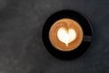 Top view of hot coffee cappuccino latte art heart shape foam in black cup on dark table background Royalty Free Stock Photo