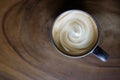 Top view of hot coffee cappuccino latte cup with spiral milk foam on wood texture table background Royalty Free Stock Photo