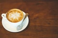 Top view hot coffee cup latte art with spoon in cafe on wooden table. Royalty Free Stock Photo