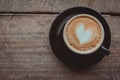 Top view, Hot coffee, heart shape with milk latte on top of black ceramic cup on wooden table in coffee shop in vintage tone, copy Royalty Free Stock Photo