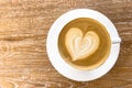 Top view of hot coffee latte cappuccino cup with heart shaped latte art milk foam on wood table background Royalty Free Stock Photo