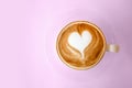 Top view of hot coffee latte with heart shaped latte art milk foam on pink pastel color sweet background.