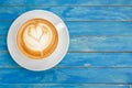 Top view hot latte coffee in white cup on blue vintage wooden ta Royalty Free Stock Photo