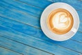 Top view hot latte coffee in white cup on blue vintage wooden ta Royalty Free Stock Photo