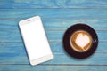 Top view hot latte coffee in white cup and smartphone with blank Royalty Free Stock Photo