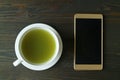 Top View of Hot Matcha Green Tea with an Empty Screen Smartphone on Dark Brown Wooden Table Royalty Free Stock Photo