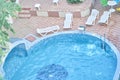 Top view of the hotel territory with round outdoor swimming pool with blue mosaic ceramic tiles, white plastic sun Royalty Free Stock Photo