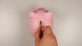 TOP VIEW: Human hand throws a coin into pink pig money box Royalty Free Stock Photo