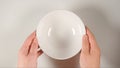 TOP VIEW: Human hands puts a white soup bowl on a white table