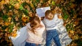 Top view imag eof little boy with young mother reading a book while lying on blanket at autumn park