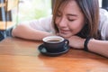 Top view image of Asian woman sit with chin resting on her hands and closing her eyes smelling hot coffee on wooden table Royalty Free Stock Photo