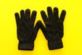 Top view image of black wool gloves over yellow background