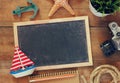 Top view image of blank old chalkboard, wooden sailboat, nautical ripe, notebook and camera. travel and adventure concept