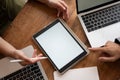 Top view image of a blank screen digital tablet mockup on a meeting table with laptops and papers Royalty Free Stock Photo