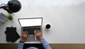 Top view image of businessman hand typing on white blank screen computer laptop at white working desk with office equipment. Royalty Free Stock Photo