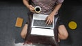 Top view image of creative man holding a hot coffee cup while typing on computer laptop that putting on his lap. Royalty Free Stock Photo