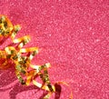 Top view image of curly golden ribbon over textured pink shiny background Royalty Free Stock Photo