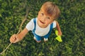 Top view image of cute kid playing with a paper plane in summer day in park. Happy little boy smiling and playing outdoors games Royalty Free Stock Photo