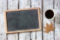 Top view image of empty blackboard next to cup of coffee , over wooden table. Royalty Free Stock Photo