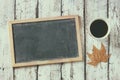 Top view image of empty blackboard next to cup of coffee , over wooden table. faded retro style filter Royalty Free Stock Photo