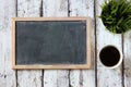 Top view image of empty blackboard next to cup of coffee , over wooden table. faded retro style filter Royalty Free Stock Photo