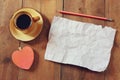 Top view image of empty crumpled paper, coffee cup and heart shape over wooden table