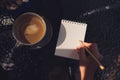 Top view image of a hand holding a pen and writing on a blank white notebook with coffee cup Royalty Free Stock Photo