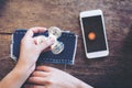 Top view image of a hand holding and playing fidget spinner with white mobile phone with blank black screen