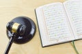 Top view image of holy Quran with law gavel on wooden background. Sharia or Islamic law concept. Large arabic word mention the