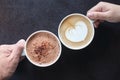 Man and woman`s hands holding coffee and hot chocolate cups with wooden table background