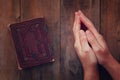 Top view image of mans hands folded in prayer next to prayer book. concept for religion, spirituality and faith