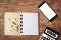 top view image of open notebook with blank pages next to chamomile flower, blank smart phone and calculator on old wooden table. Royalty Free Stock Photo