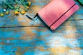 Top view image of open notebook on the old blue painted wooden table with yellow flowers. Blank notebook with flower and green pen Royalty Free Stock Photo