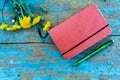 Top view image of open notebook on the old blue painted wooden table with yellow flowers. Blank notebook with flower and green pen Royalty Free Stock Photo