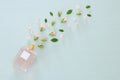 Top view image of perfume bottle with rose petals flowers over pastel blue background. Floral scent concept.