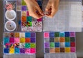 Top view image of a person trying to make a bracelet with a set of beading kit supplies; craft