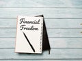Top view image phrase financial freedom written on the notebook with a pen on the table. Royalty Free Stock Photo