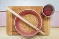 Top view image of pink bowl with Chinese curly noodles, chopsticks