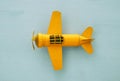 Top view image of retro yellow metal toy airplane over blue background.