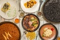 Top view image of Spanish dishes and paellas. Seafood paella, black rice paella with squid, cod al pil pil,