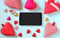 Top view image of tablet, colorful heart shape chocolates, fabric hearts on wooden background. valentine's day celebration concept