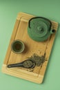 Top view image of traditional Asian green teapot with porcelain tea cup and green tea spoon on bamboo table Royalty Free Stock Photo
