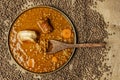 Top view image traditional lentil stew from northern Spain with wooden spoon, bacon, chorizo and some vegetables scattered on a