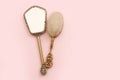Top view image of vintage hand mirror and hair comb over pastel pink background