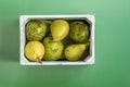 Top view image of white painted wooden crate full of ripe pears of different varieties on plain green background Royalty Free Stock Photo