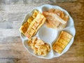 Top view image, a white plate of yellow brown crunchy and crispy roti or bolloon bread fired Indian style snack, on wooden table