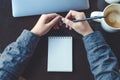 Top view image of a woman`s hands holding a pencil to writing on a blank notebook with laptop and coffee cup Royalty Free Stock Photo