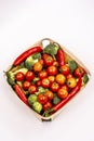 Top view image of wooden basket with bulk cherry tomatoes, broccoli pieces, red hot chili peppers Royalty Free Stock Photo